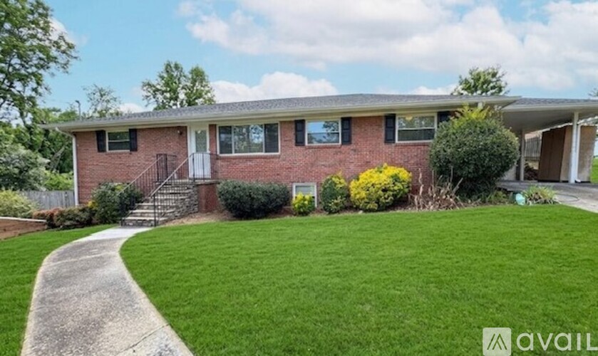 A house with a red brick exterior and a green lawn in front.