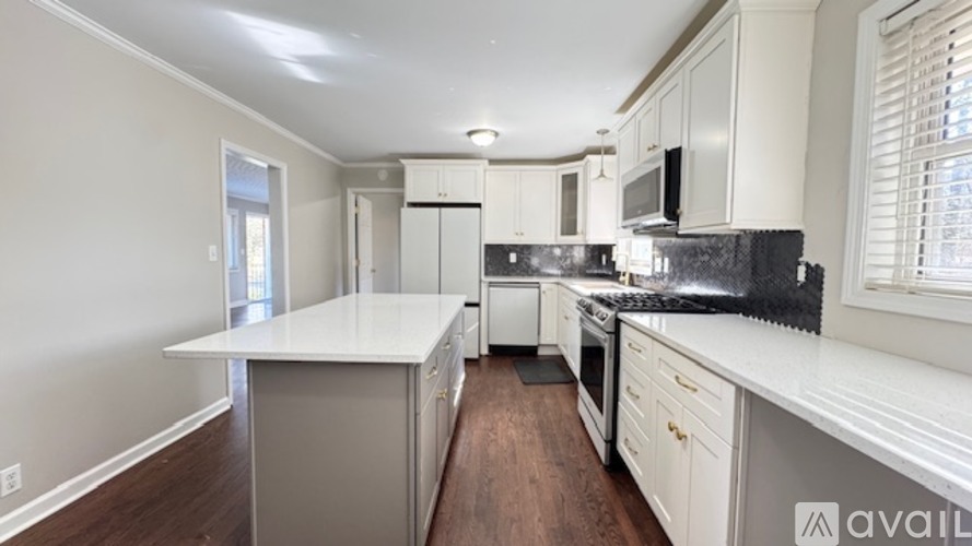 A kitchen with white countertops and wooden floors.