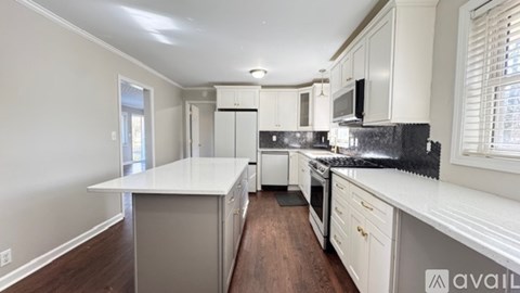 A kitchen with white countertops and wooden floors.