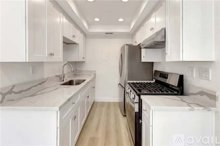 A modern kitchen with white cabinets and a marble countertop.