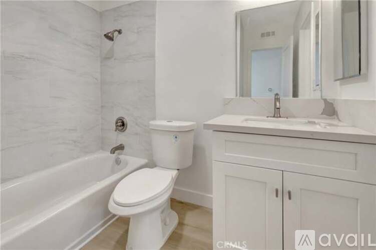 A white bathroom with a toilet, sink, and bathtub.