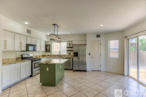 A kitchen with white cabinets and a green island.
