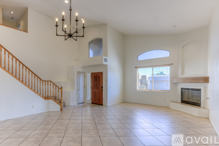 A spacious living room with a fireplace and a staircase.
