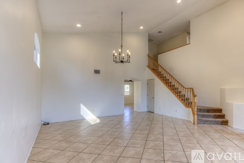 A spacious room with a staircase and a chandelier.