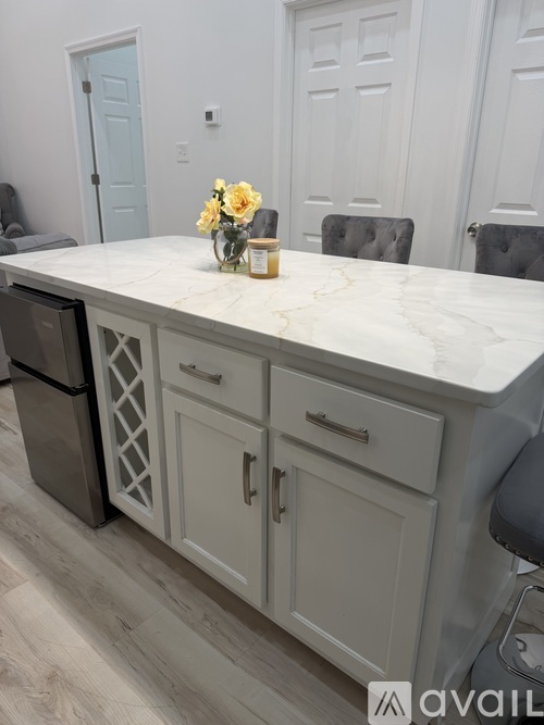 A kitchen island with a marble top and white cabinets.