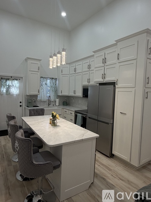 A kitchen with a white island and grey chairs.