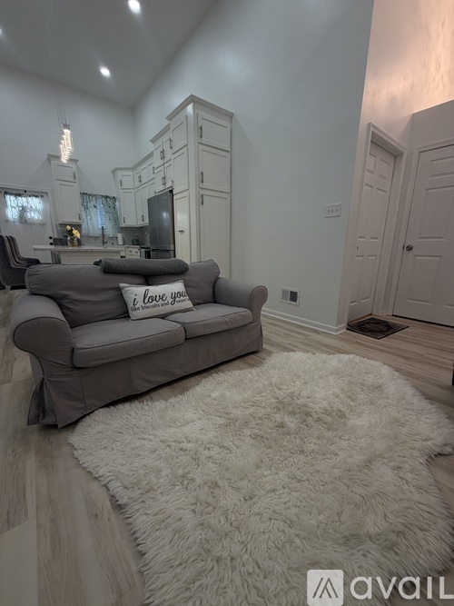 A grey couch with a pillow that says "i love you" in a living room.