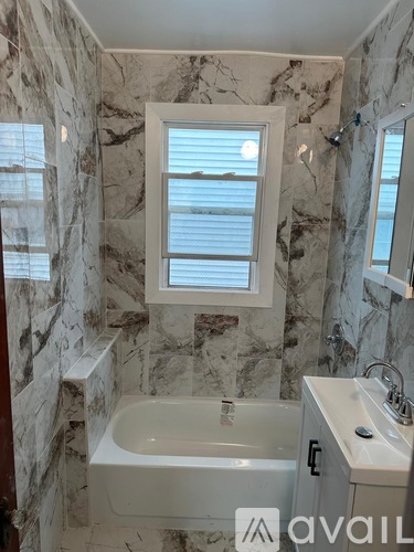 A bathroom with marble walls and a tub.