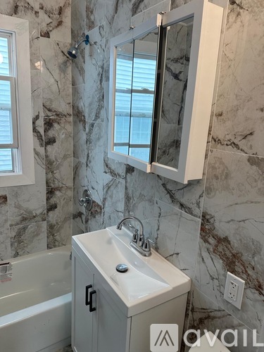 A bathroom with a marble wall and a white sink cabinet.