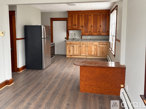 A kitchen with wooden cabinets and a black refrigerator.