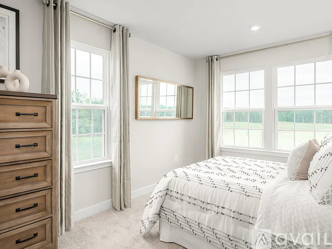 A bedroom with a large bed and a window with curtains.