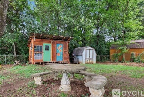 A wooden structure with a green door is surrounded by trees.