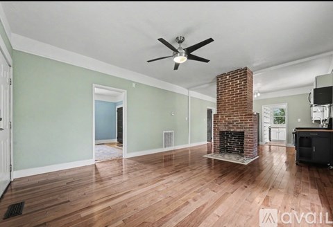 A living room with a fireplace and a ceiling fan.