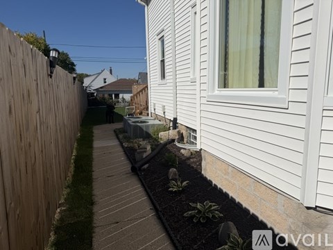 A white house with a wooden fence and a garden bed in front.