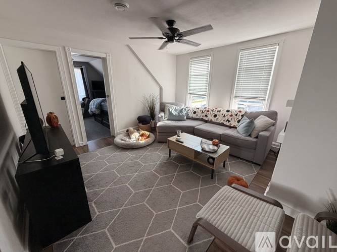 A living room with a grey sofa, a black entertainment center, and a ceiling fan.