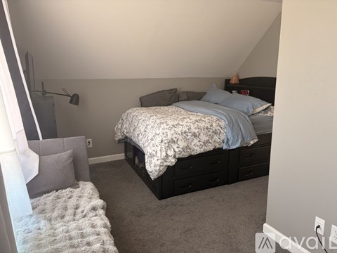 A bedroom with a bed, nightstand, and a grey rug.