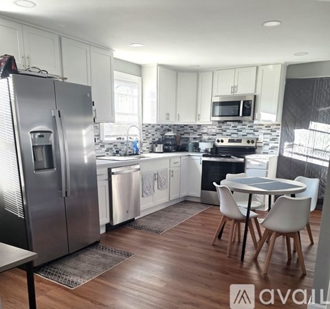 A modern kitchen with a refrigerator, stove, and dining table.