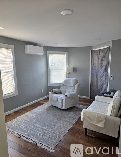 A living room with two white chairs and a rug.