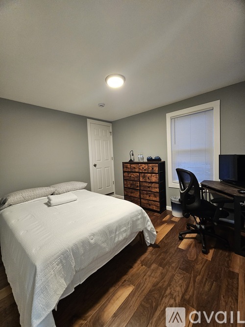 A bedroom with a bed, desk, and chair.