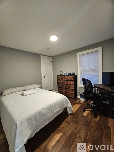 A bedroom with a bed, desk, and chair.