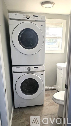 A stacked white front loading washer and dryer in a small laundry room.