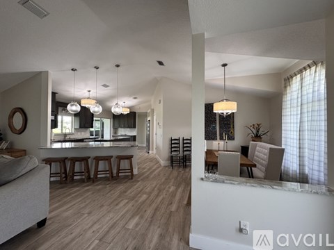 A modern living room with a kitchen in the background.
