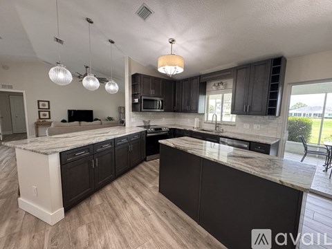 A kitchen with dark wood cabinets and a marble countertop.