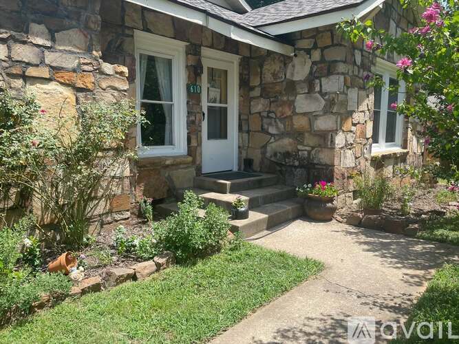 A house with a white door and windows surrounded by greenery.