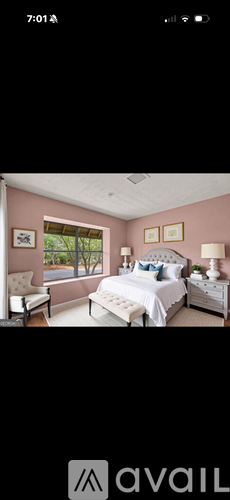 A bedroom with a large bed and a window overlooking a tree-filled landscape.