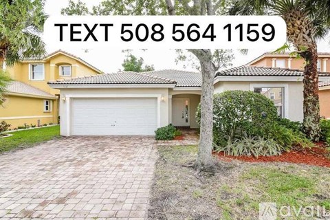 A house with a driveway and a palm tree in front.