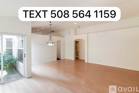 A spacious room with wooden flooring and a hanging light fixture.