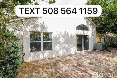 A house with a white exterior and a brick patio is for sale.