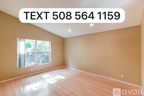 A room with wooden flooring and a window letting in sunlight.