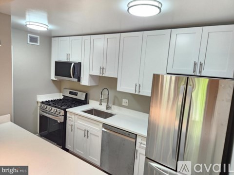A kitchen with white cabinets and a stainless steel refrigerator.
