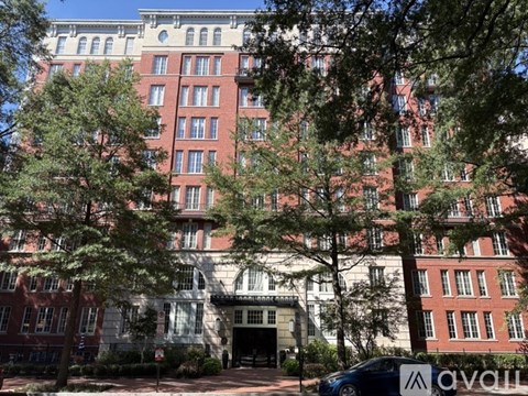 A tall red brick building with a white entrance and trees in front.