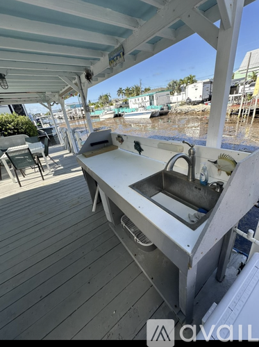 A white outdoor kitchen with a sink and grill.