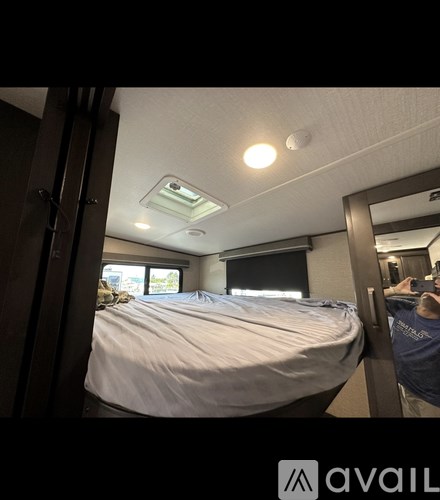 A bedroom with a bed, mirror, and a window with blinds.