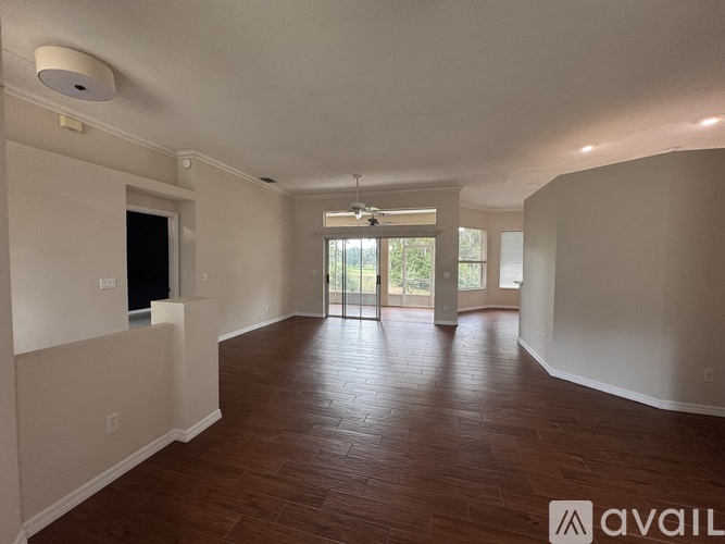 A spacious room with wooden flooring and a sliding glass door leading to a balcony.