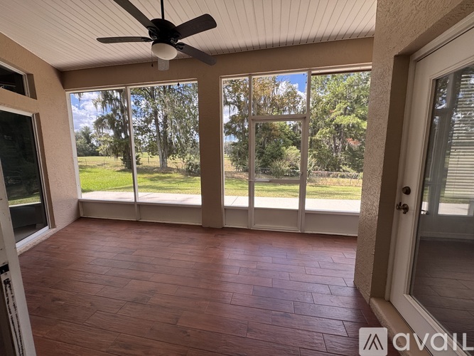 A room with a ceiling fan and sliding glass doors leading to a grassy area.