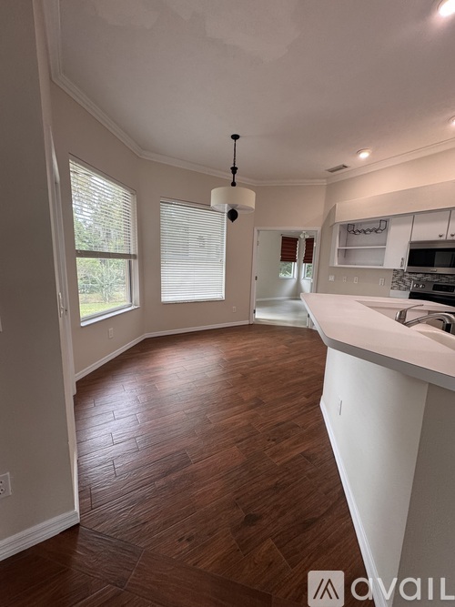 A kitchen with white cabinets and a wooden floor.