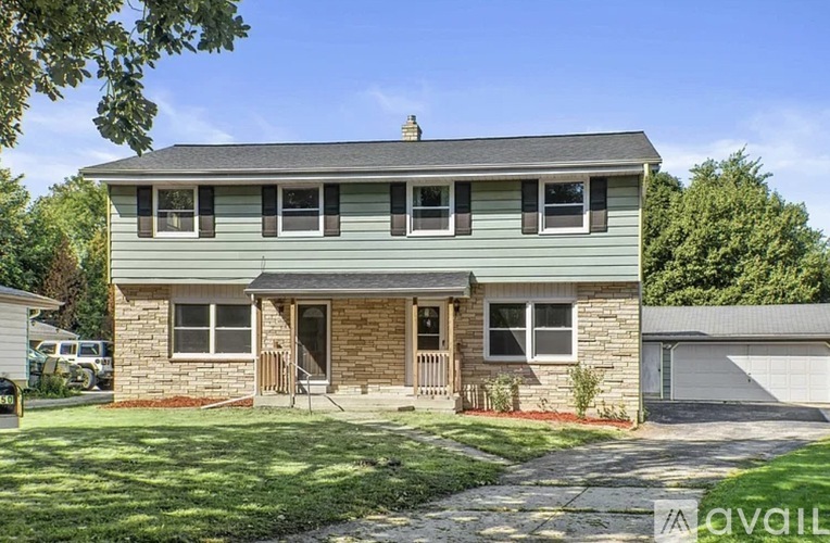A house with a green front yard and a driveway leading to the front door.