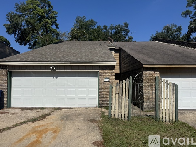 A house with a white garage door and a wooden fence in front.