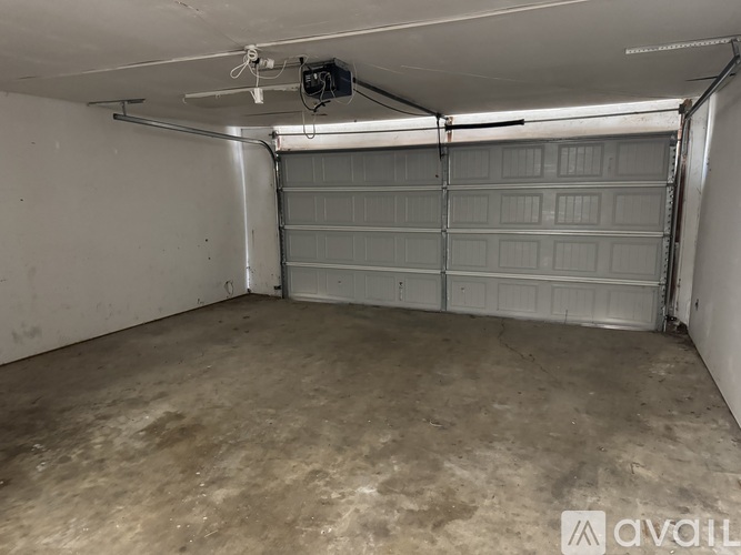 A spacious garage with a closed white door and a fan on the ceiling.