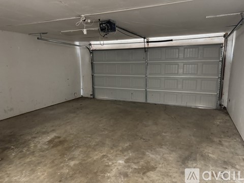 A spacious garage with a closed white door and a fan on the ceiling.