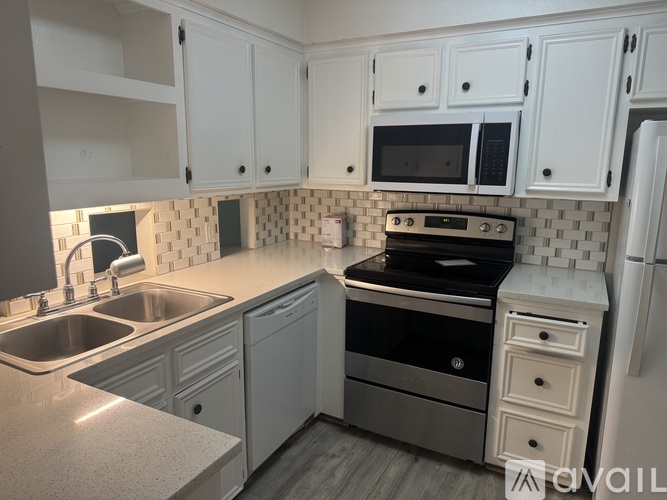 A kitchen with white cabinets and a black stove top oven.