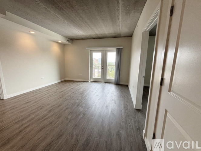 A room with wooden flooring and a slanted ceiling with a doorway leading to a balcony.