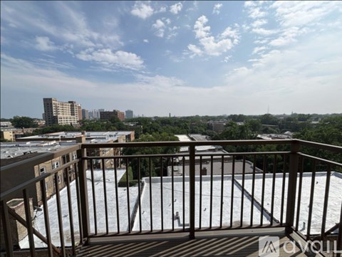A balcony with a metal railing overlooks a cityscape.