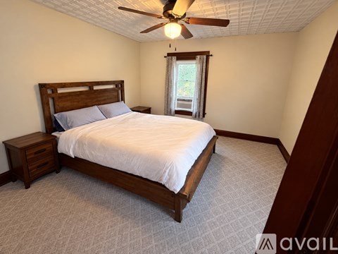A bedroom with a bed, nightstand, and window.