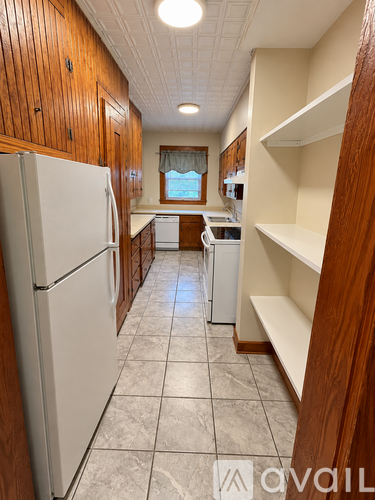 A kitchen with a white refrigerator and wooden cabinets.