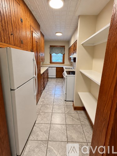 A kitchen with a white refrigerator and wooden cabinets.